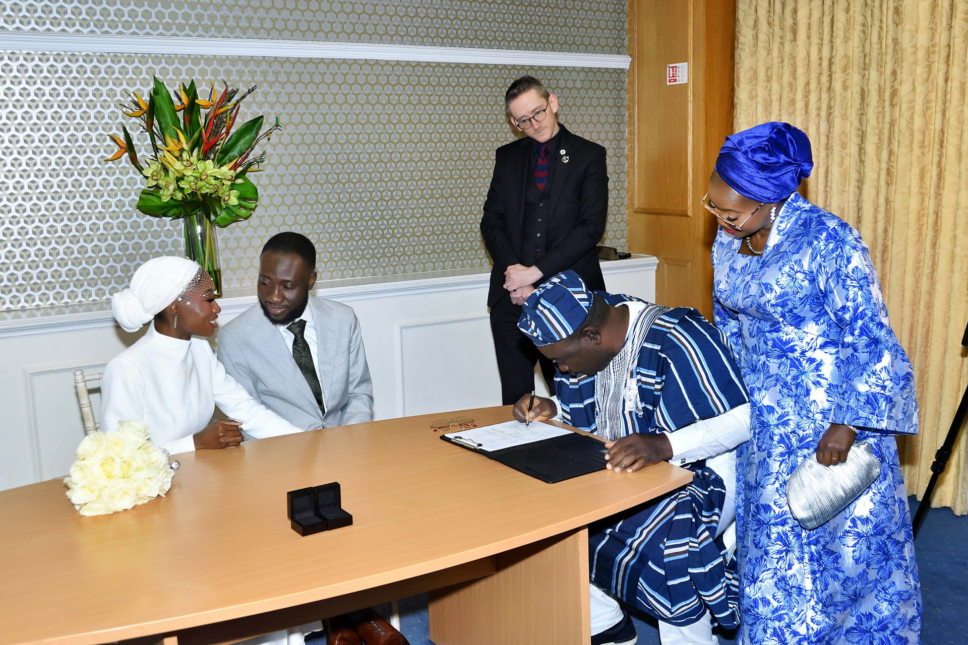 Bride and groom watching a witness sign the marriage register at their civil wedding ceremony