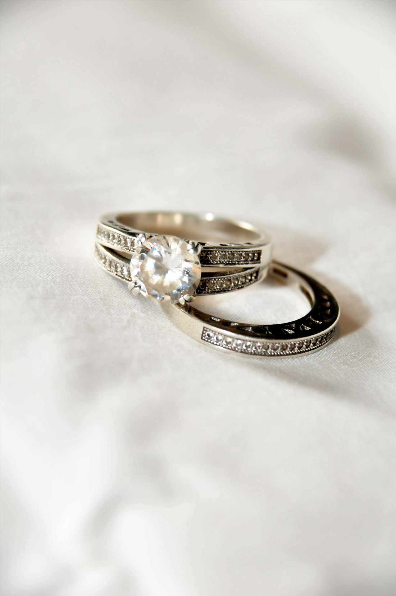 Close-up of a diamond engagement ring and matching wedding band resting on ivory silk